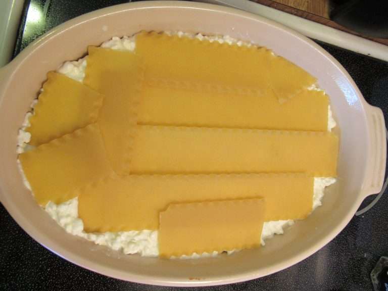 Uncooked lasagna noodles layered on Mom's lasagna 10 step recipe.