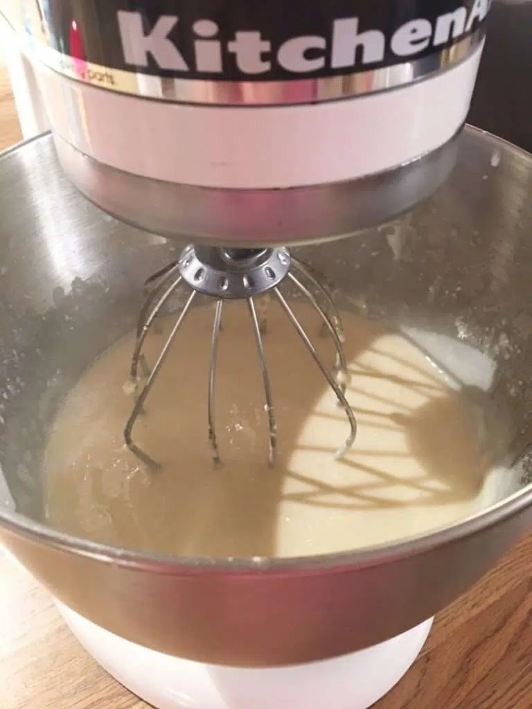Electric stand mixer with cream of coconut poke cake ingredients.