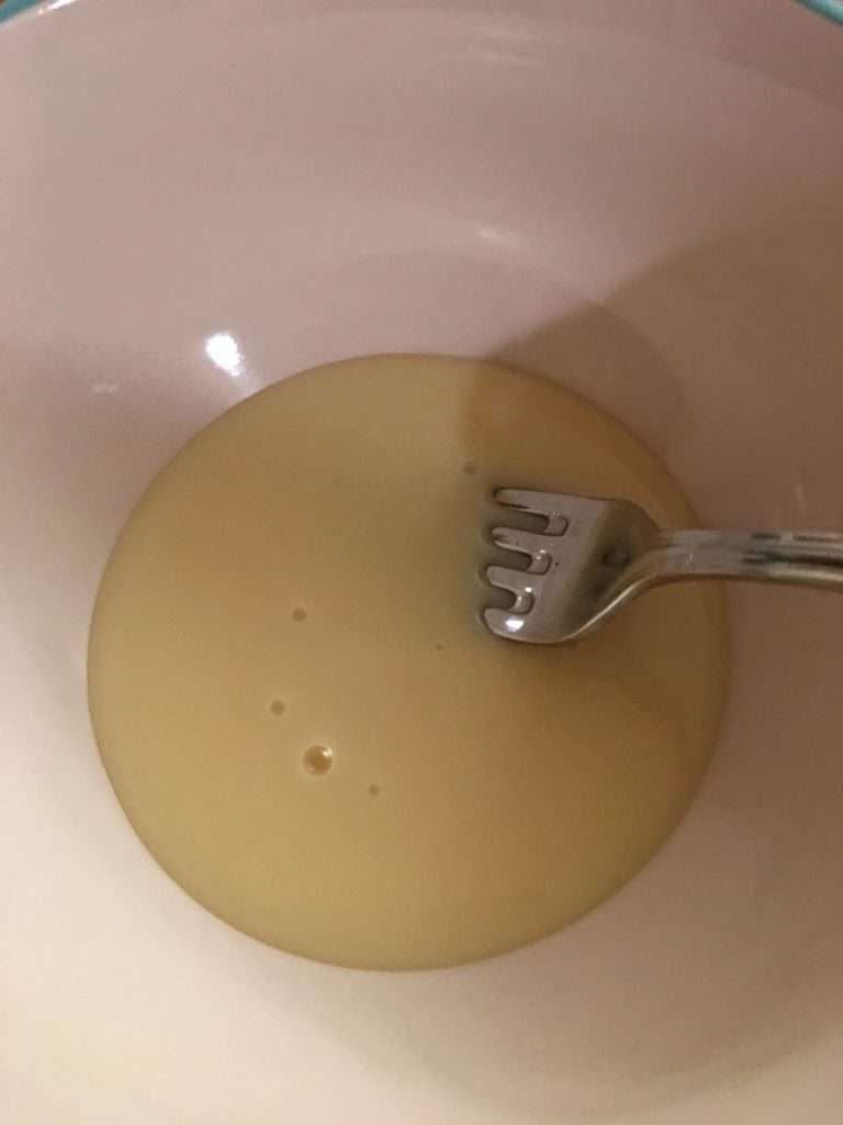 The Easiest Coconut Cake Recipe Ever 4 cream of coconut and sweetened condensed milk in white mixing bowl with silver fork
