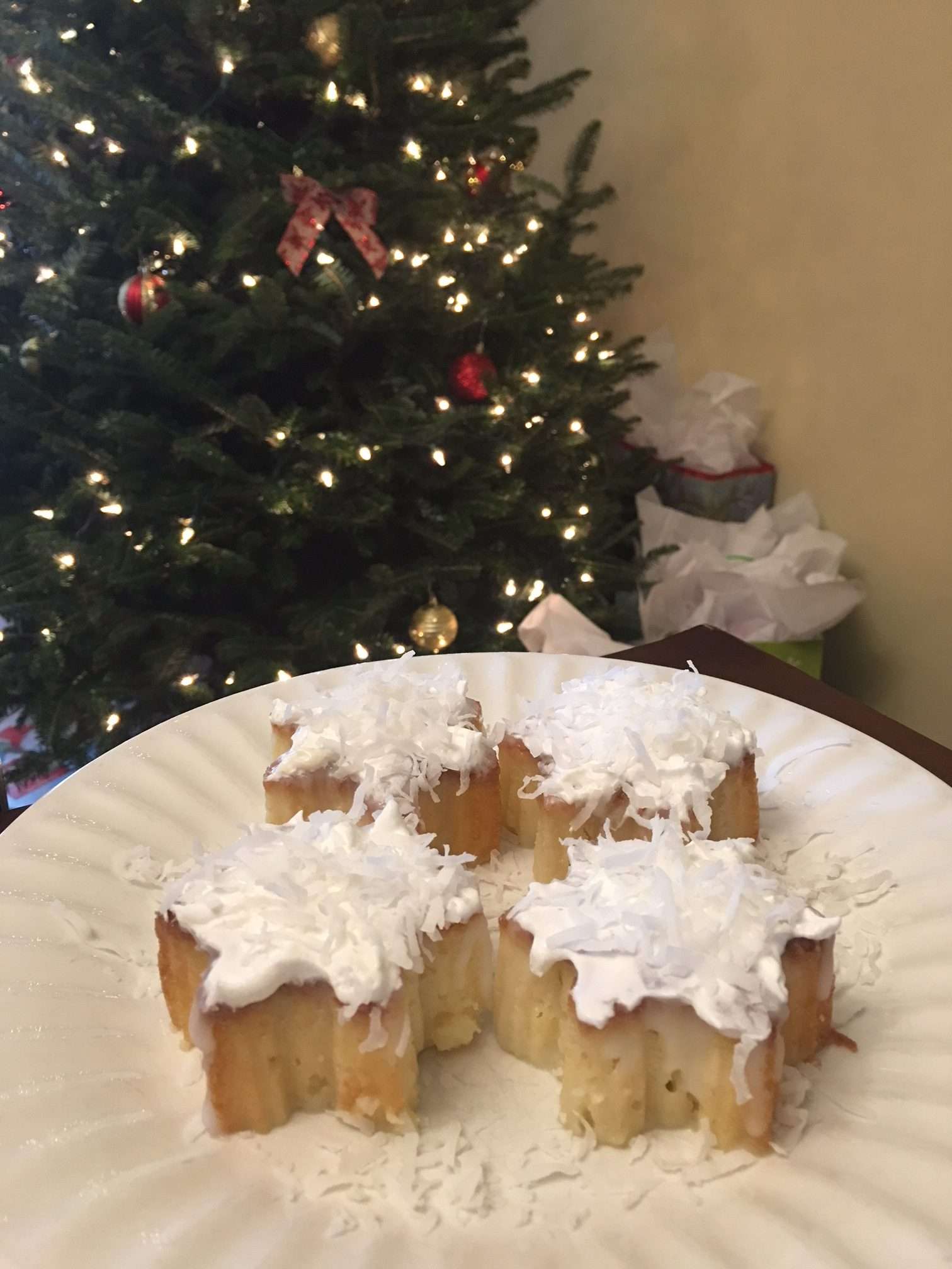 White plate with cream of coconut poke cakes, Christmas tree in the background.