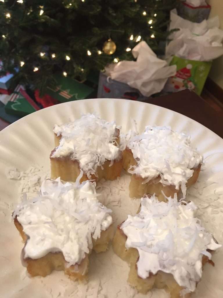 The Easiest Coconut Cake Recipe Ever 9 four coconut cake snowflakes on white plate with coconut icing and flakes on top