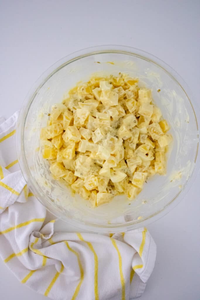 Southern Potato Salad Recipe (My Mom's Famous Recipe) 7 Overhead view of Southern Potato salad ingredients in a mixing bowl, white and yellow checkered kitchen towel on a white countertop.