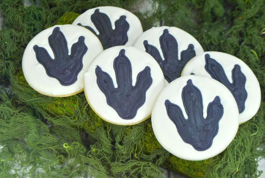 Dinosaur cookies on green material that resembles moss.