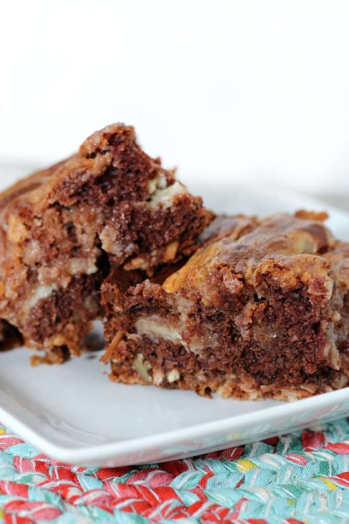 Easy German Chocolate Bars 3 german chocolate cheesecake bars on white plate with light blue and red placemat