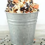 Halloween popcorn in a metal bucket on a wooden countertop.