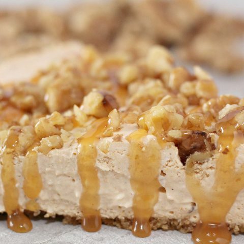 Close up of no bake pumpkin cheesecake topped with chopped walnuts and caramel topping.