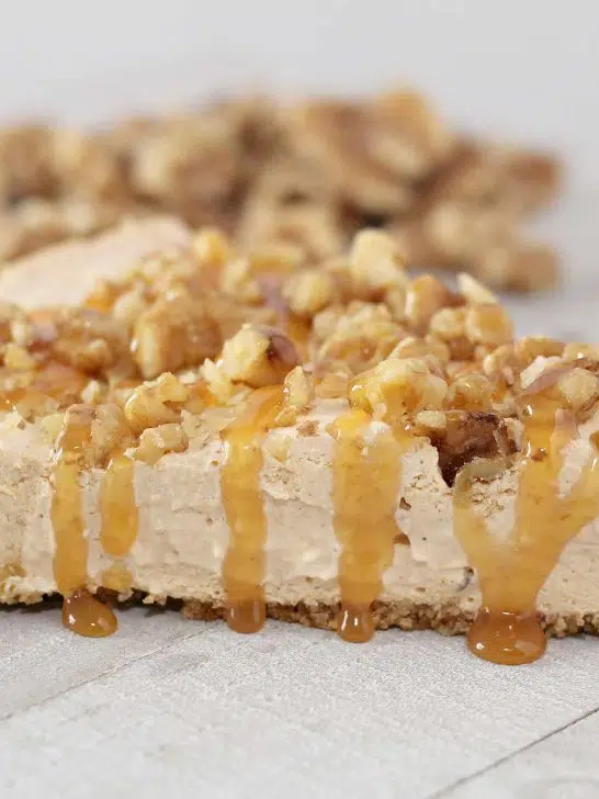 Slice of no bake pumpkin cheesecake topped with chopped walnuts and caramel topping.