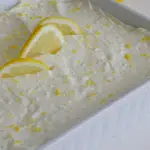 6 ingredient lemon bars in white pan with lemon slices and zest