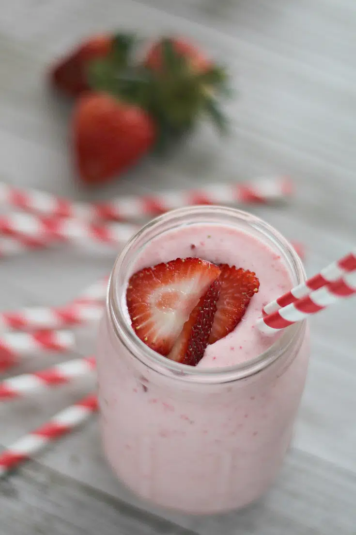 strawberry lemonade milkshake in glass with red straw