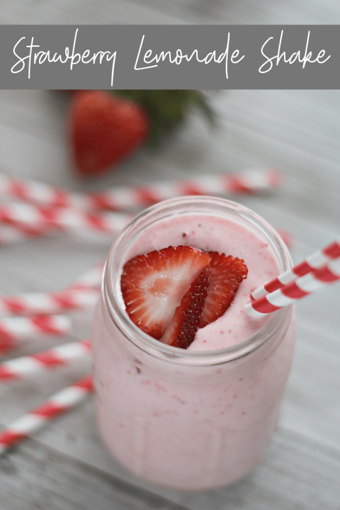 strawberry lemonade milkshake in glass with strawberries on top and red straw
