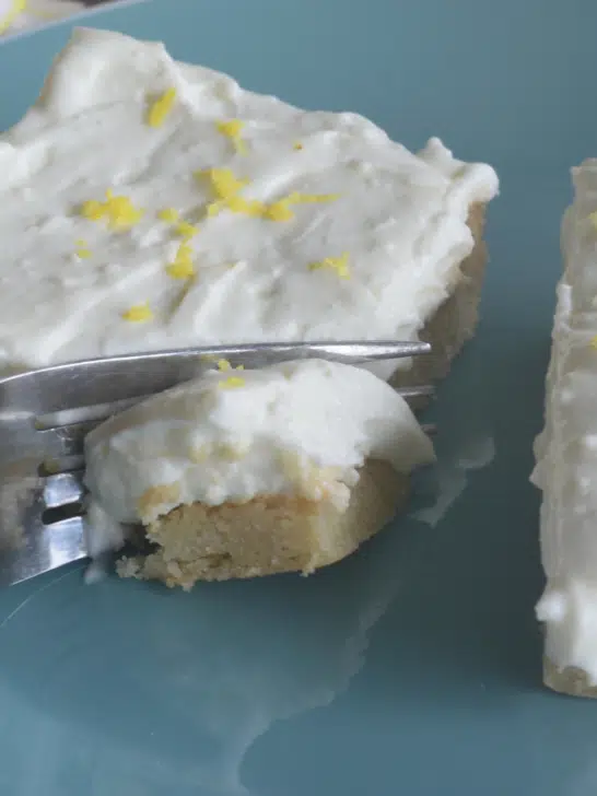2 lemon bars on blue plate with fork going through one