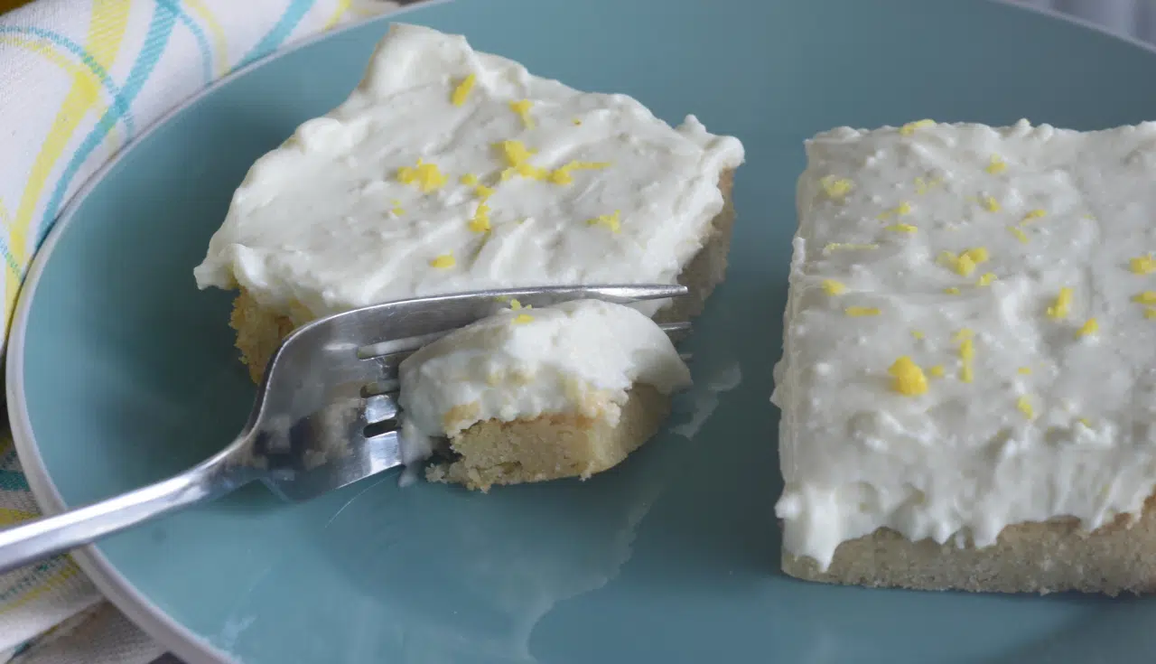 2 lemon bars on blue plate with fork going through one