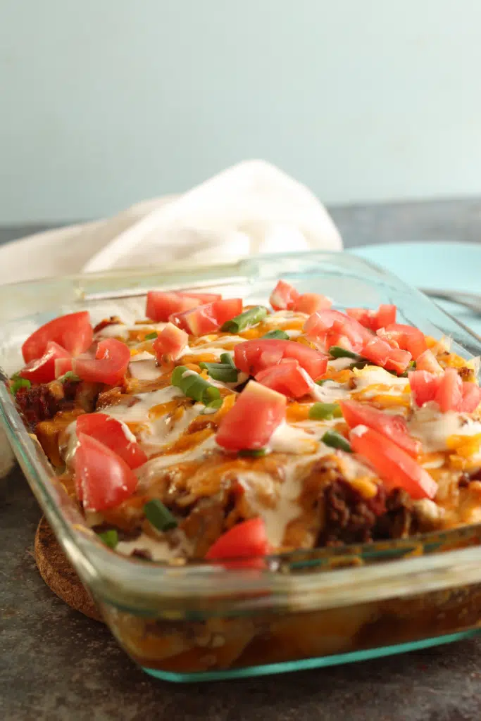 Taco potato bake in dish with chopped tomatoes and green onions.