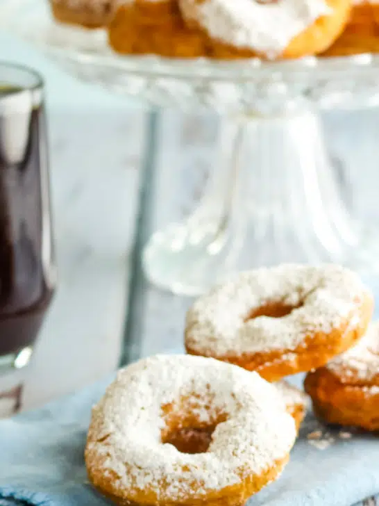donuts on blue napkin next to cup of coffee