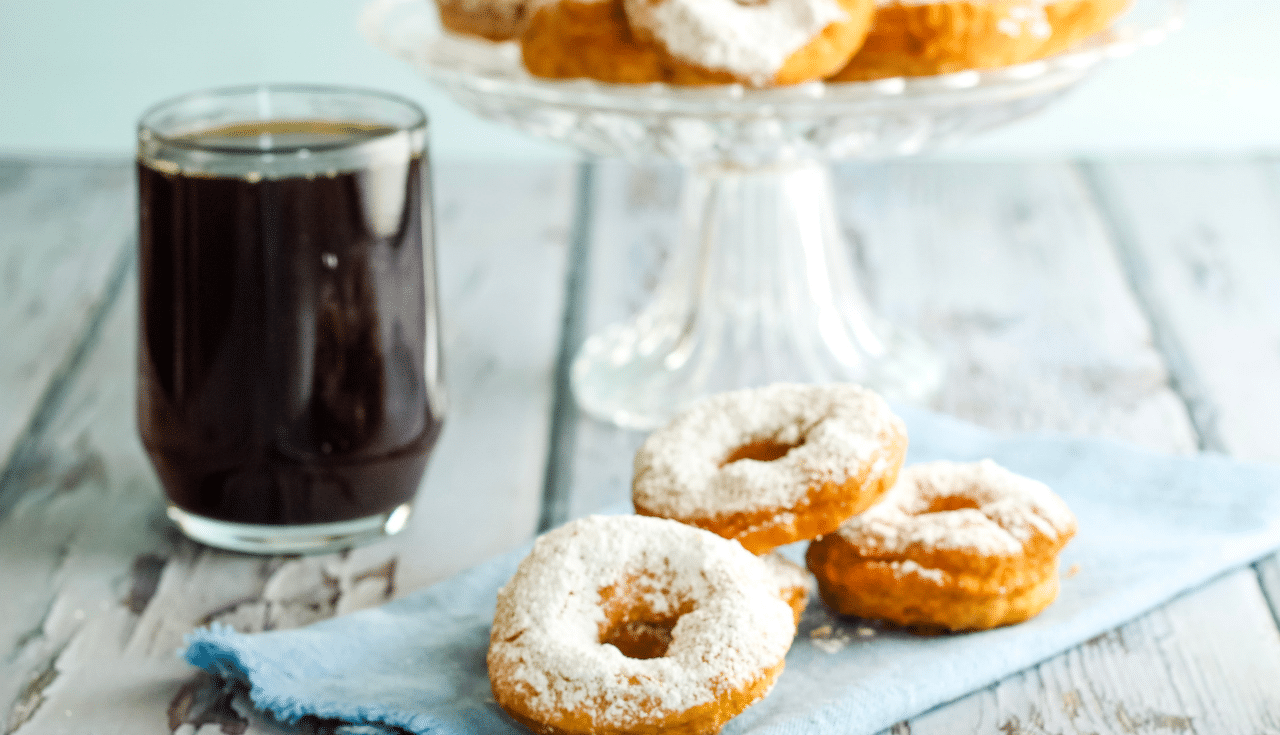 donuts on blue napkin next to cup of coffee