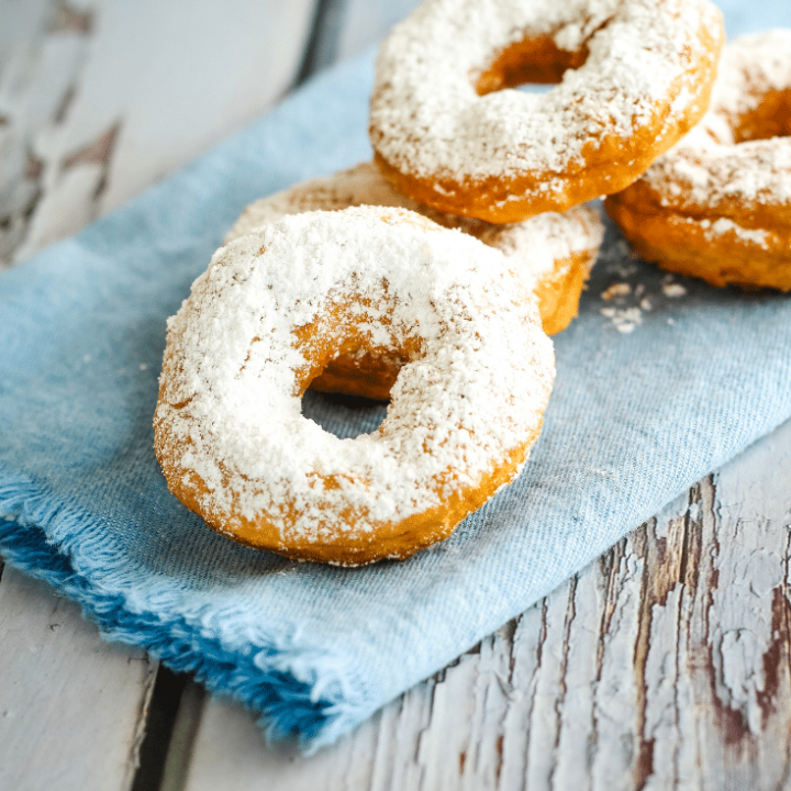 Old Fashioned Donuts 6 4 old fashioned donuts on blue napkin that's placed on a wooden surface.