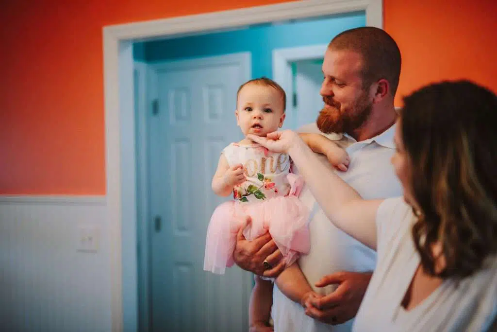 Mom and dad holding baby girl in first birthday outfit tutu