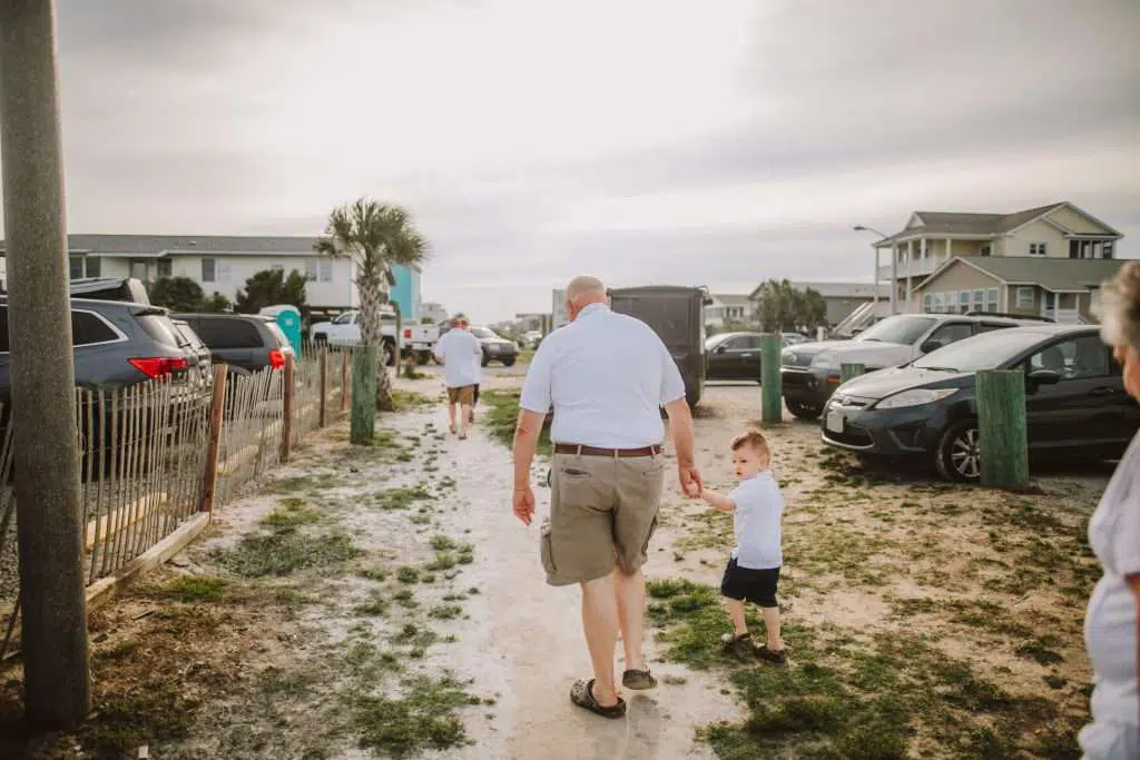Toddler and grandpa walking to beach in matching shirts