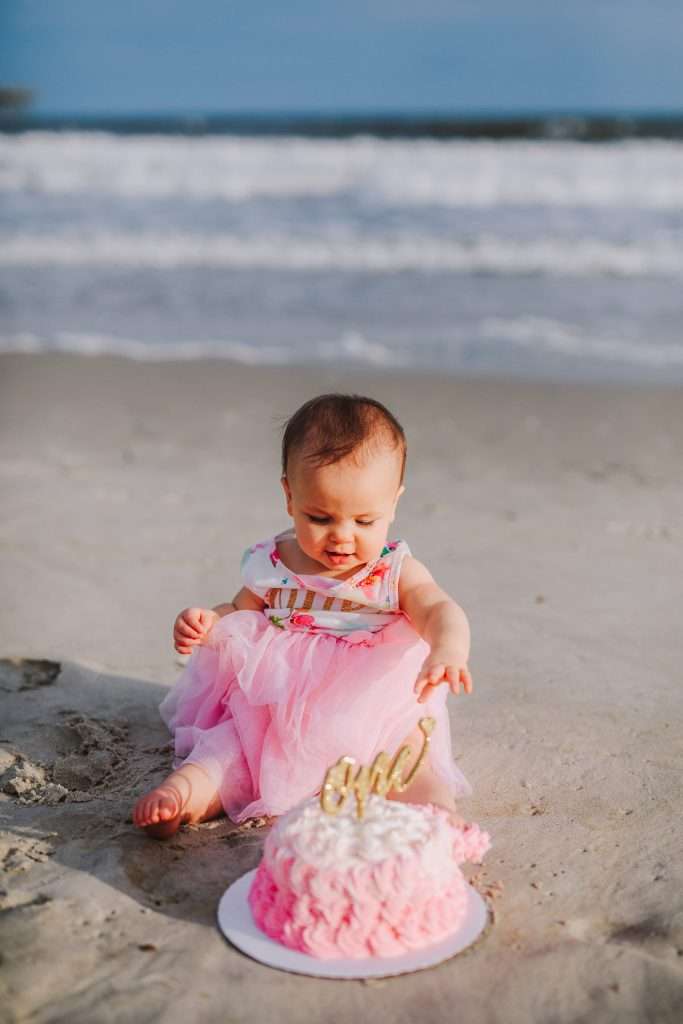 First birthday cake smash session on the beach pink rosette cake with gold cake topper