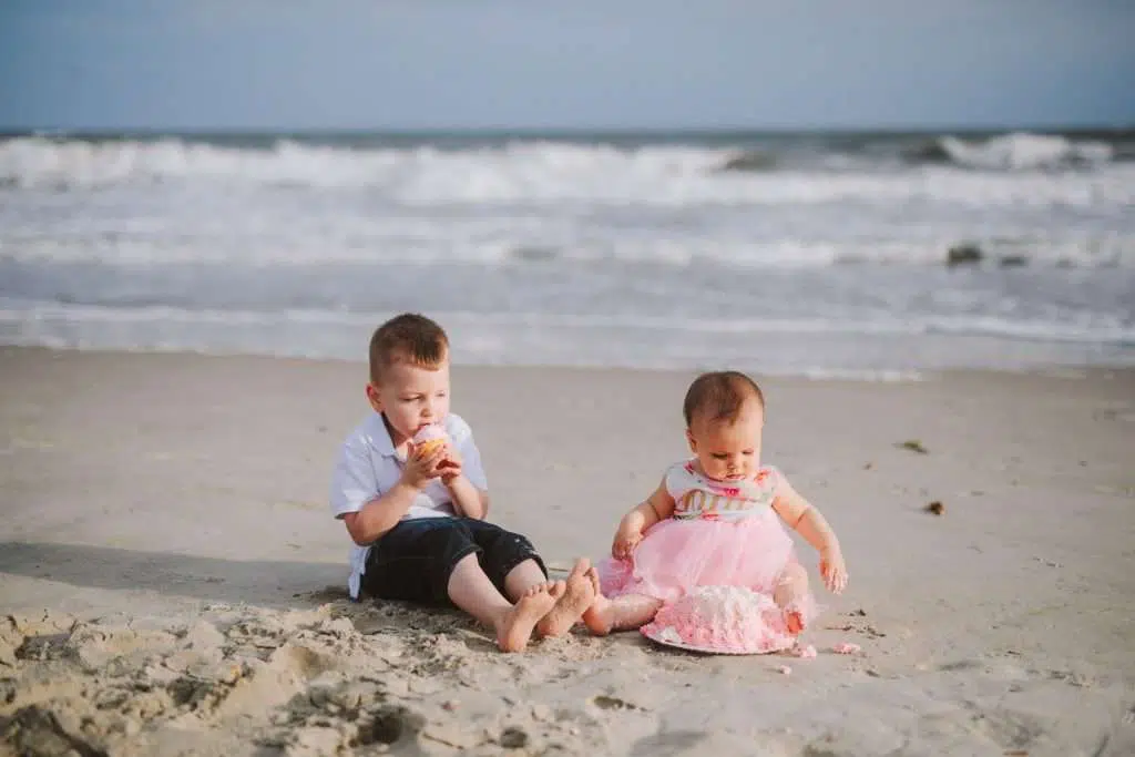 Toddler big brother and one year old on beach for cake smash session