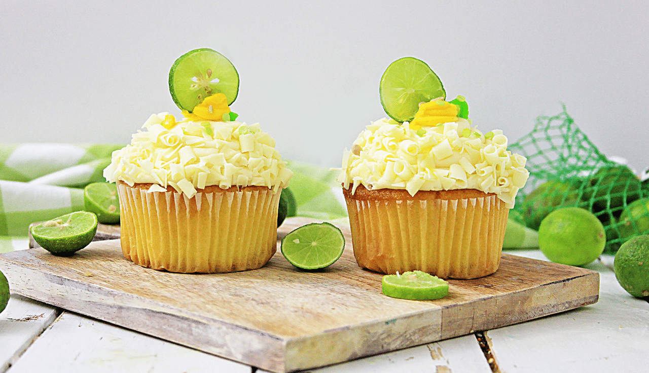 2 key lime cupcakes next to each other on wooden board