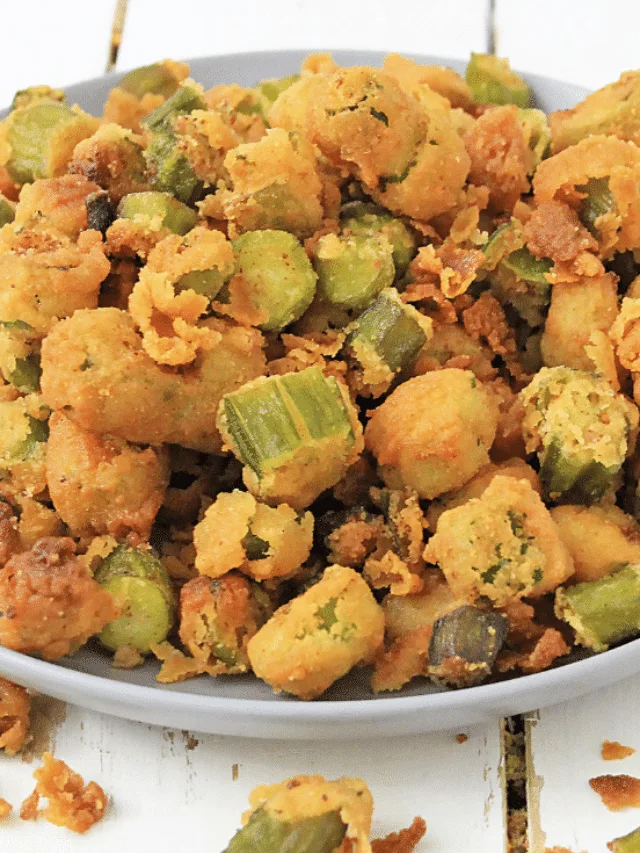 Fried Okra Recipe 3 A plate of crispy, golden-brown fried okra pieces, coated in a seasoned breading, is served on a gray plate atop a white surface.