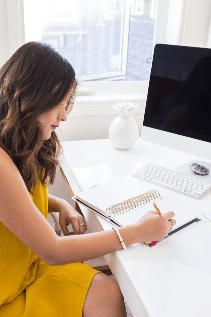 woman sitting at desk, writing in journal