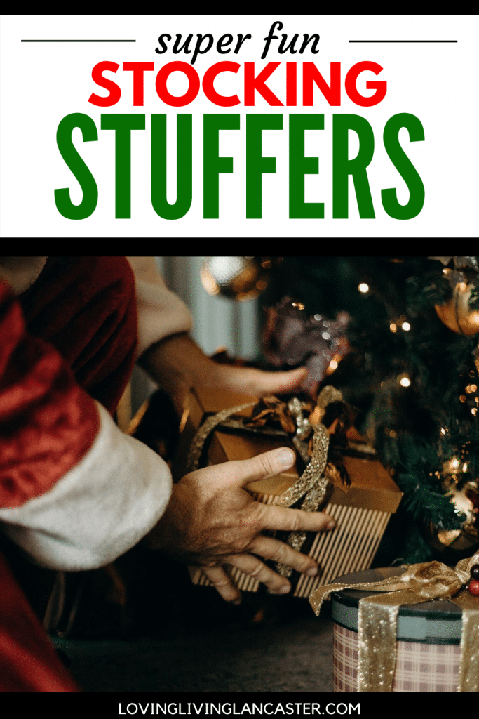 person in santa outfit placing gift under tree