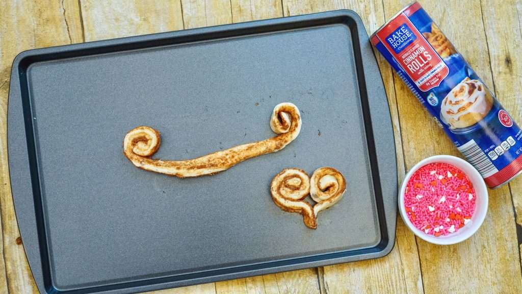 Cinnamon rolls on baking sheet put into heart shape