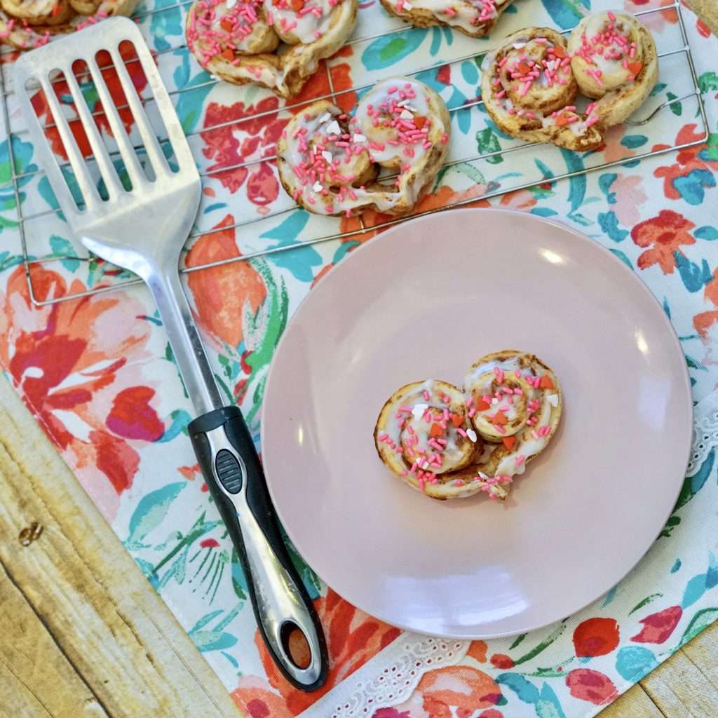 Heart shaped cinnamon rolls decorated with sprinkles on plate