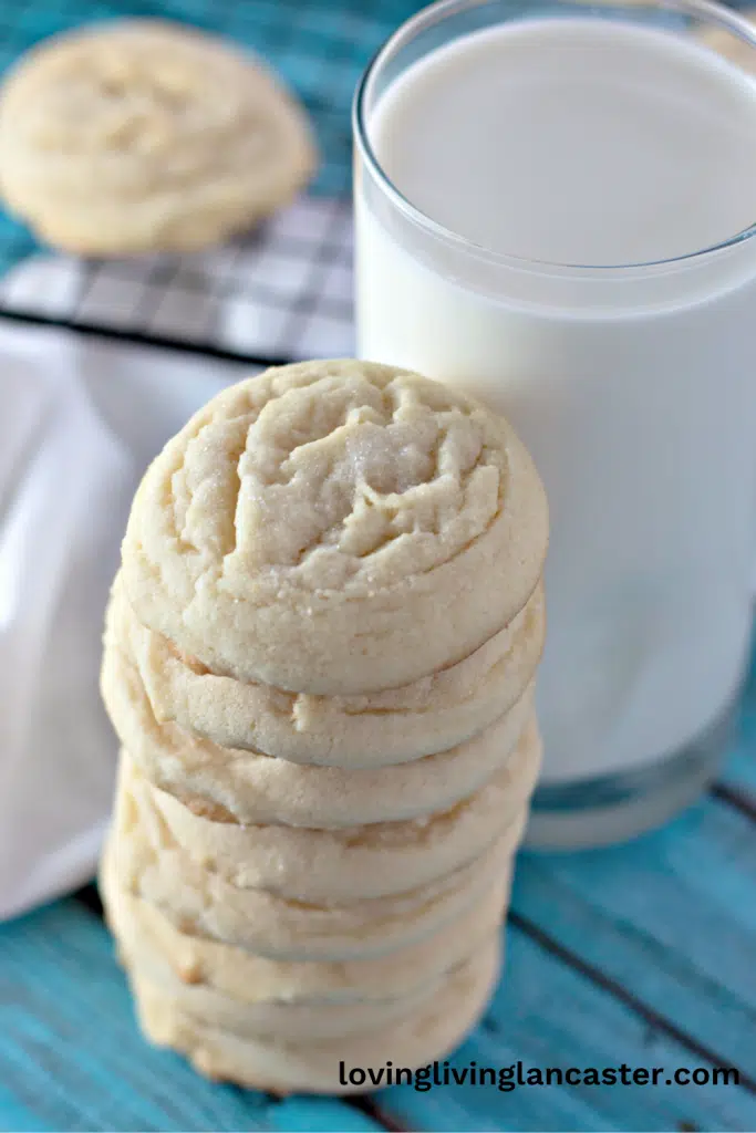 Stacked Amish sugar cookies with a glass of milk, ready to be enjoyed. 