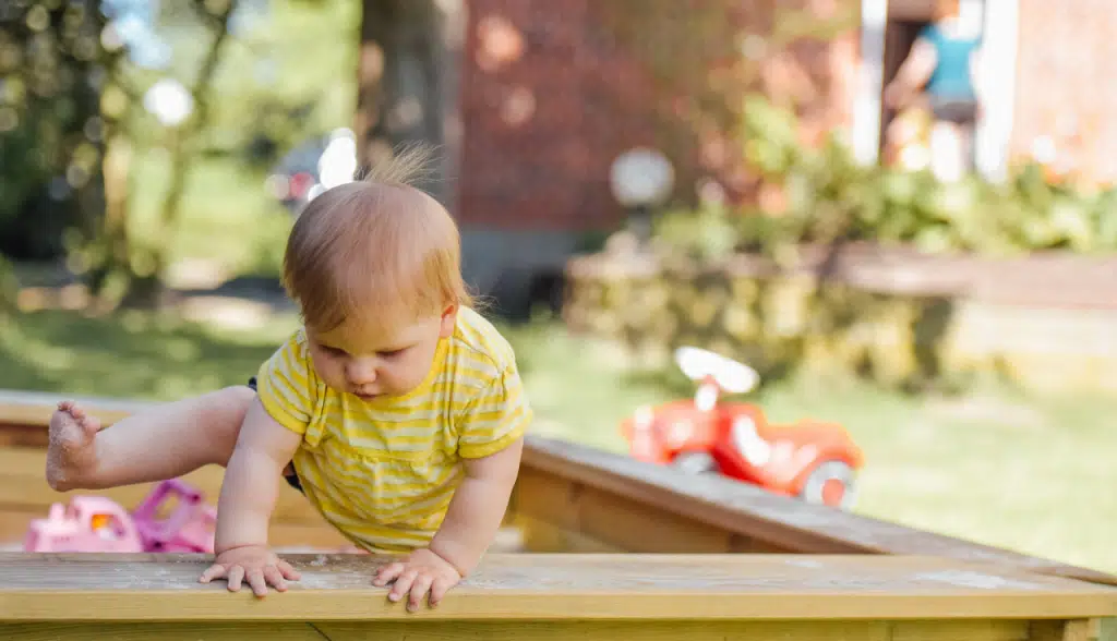 toddler climbing out of sandbox