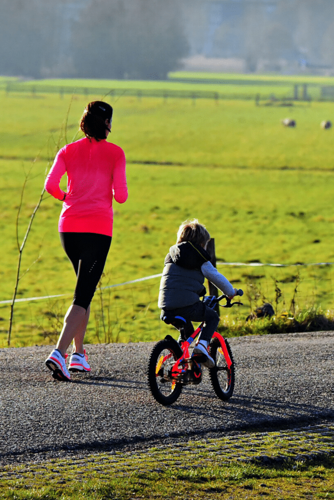 Outdoor Activities To Enjoy With Your Toddler 9 mom jogging next to kid riding his bike.