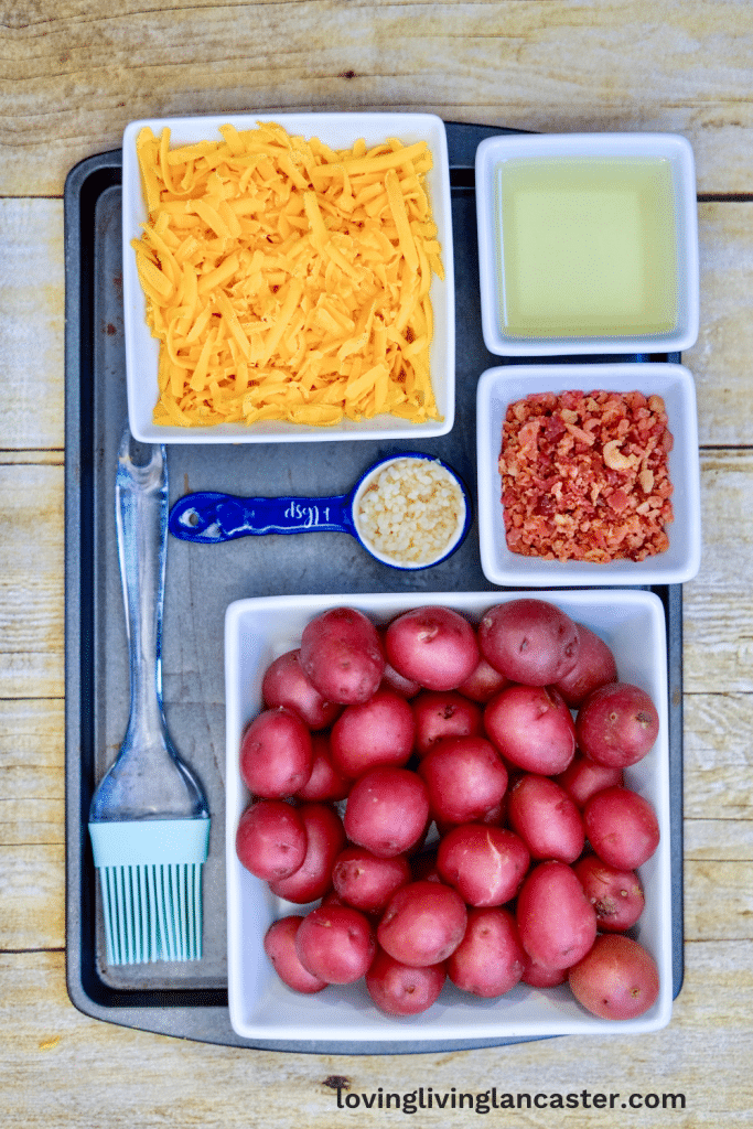 Loaded Smashed Potatoes 7 potatoes cheese bacon oil and garlic in white dishes on a baking sheet