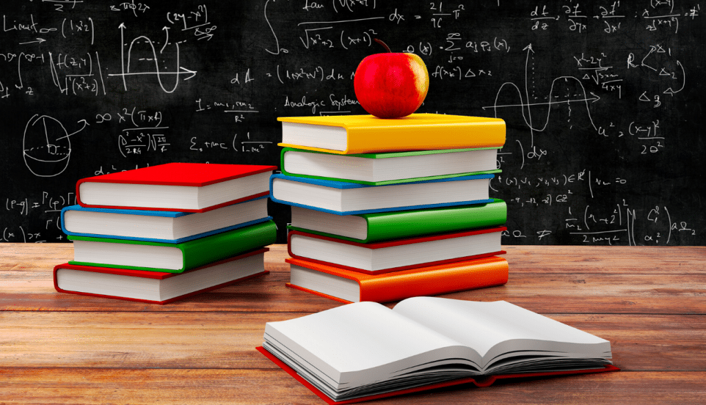 books and apple in front of chalkboard