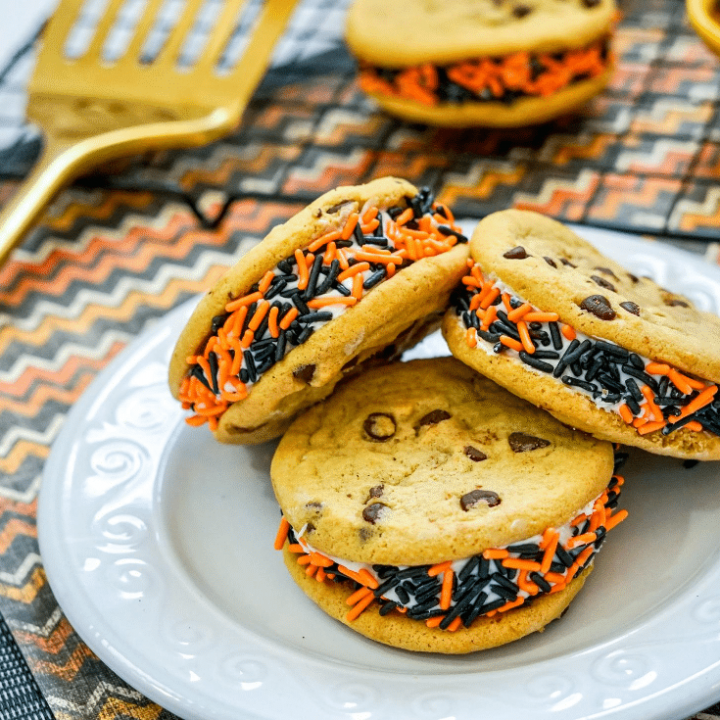 Chocolate Chip Halloween Cookies 14 Three chocolate chip Halloween cookies on a white plate, additional decorative Halloween cookies on a cooling rack on a decorative mat.