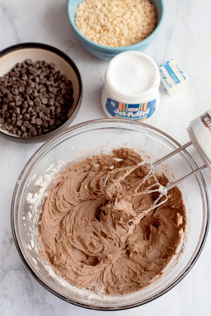 Chocolate Marshmallow Bars 16 Electric stand mixer mixing the wet and dry ingredients in a large glass mixing bowl.