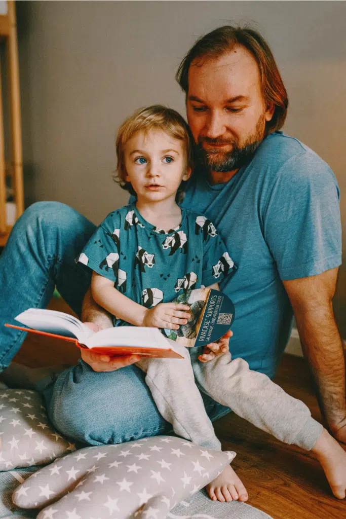 child sitting on dads lap while dad reads to them
