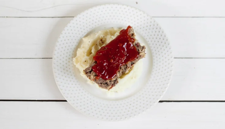 Venison Meatloaf with ketchup sauce on mashed potatoes on circle white plate