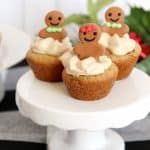 Gingerbread cupcakes on a cake stand, topped with cream cheese filling and gingerbread men.