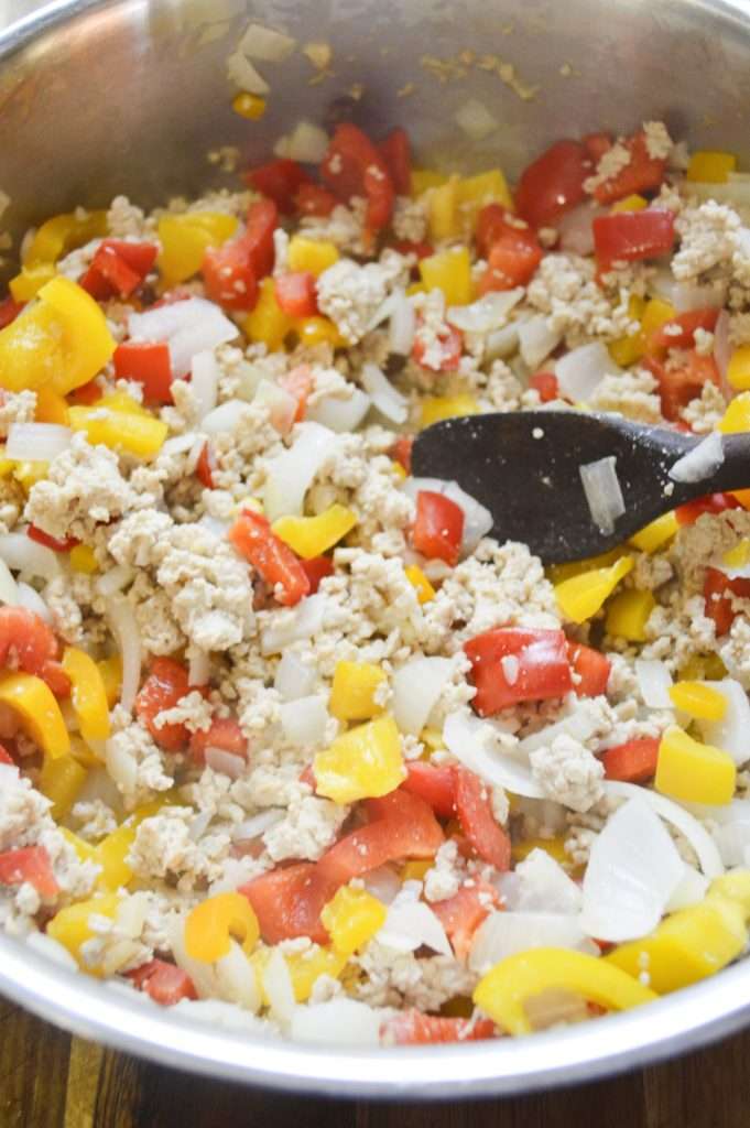 Taco Biscuit Cups 7 Ground chicken with red and yellow bell peppers cooking on the stovetop.