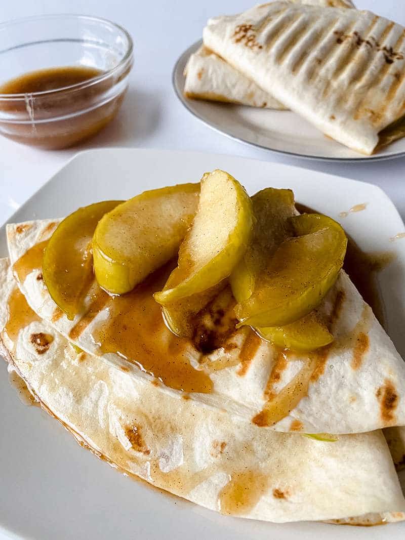 Completed caramel apple tortilla recipe with caramel drizzle and sliced apples