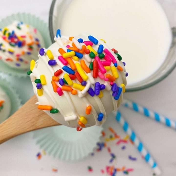 White Chocolate Hot Chocolate Bombs 5 White hot Chocolate Bomb on a spoon with rainbow sprinkles