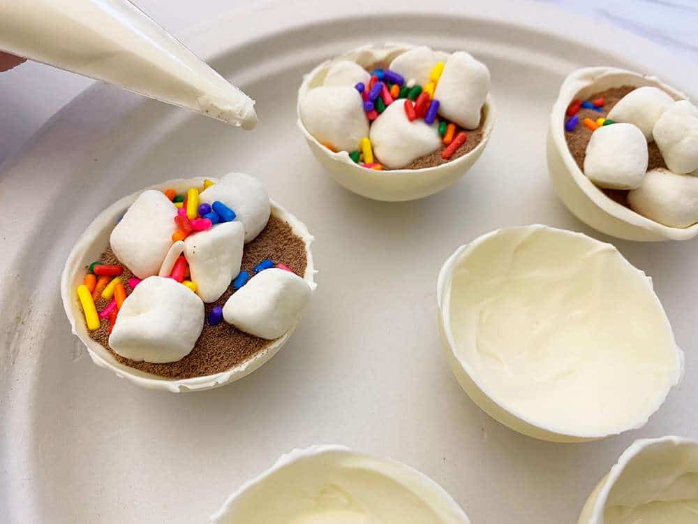 White chocolate hot chocolate bombs being assembled on a plate
