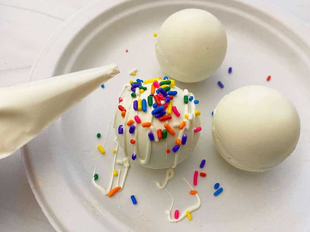White Chocolate Hot Chocolate Bombs 3 White chocolate hot chocolate bombs being decorated on a plate