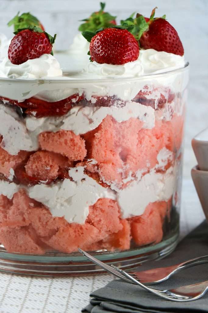 finished layered strawberry trifle recipe in clear container with strawberries on top 