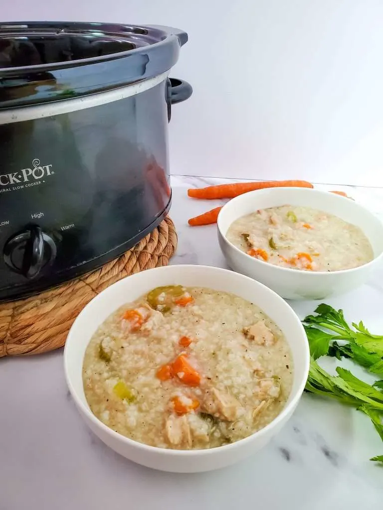 crockpot turkey and rice soup in two bowls with a crockpot in the background