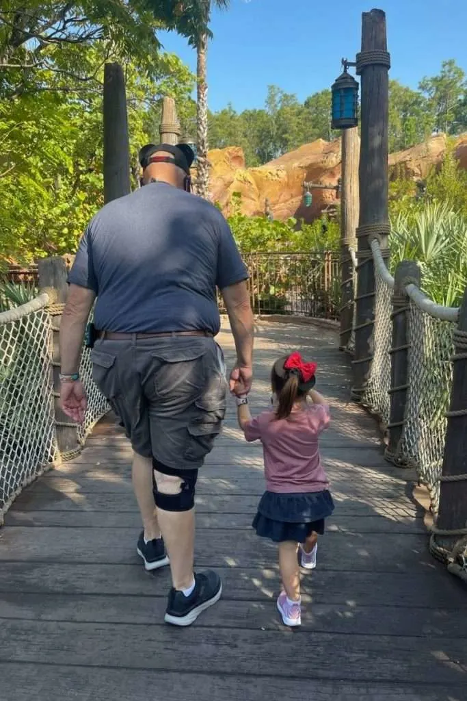 grandpa and granddaughter in queue to Little Mermaid ride at Magic Kingdom