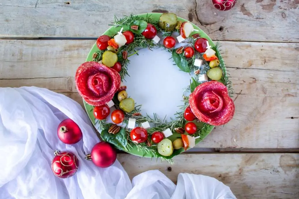 overhead view of Charcuterie Christmas Wreath on wooden table with christmas ornaments on side