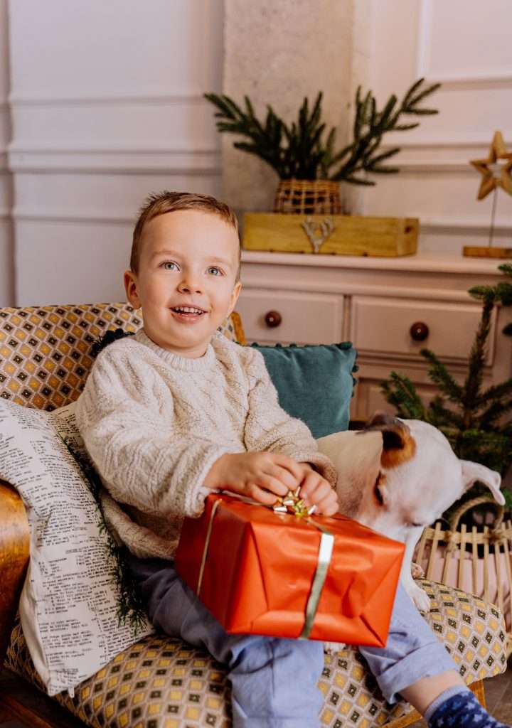 little boy sitting with a chrristmas gift on his lap